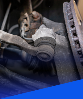 A close-up view of a vehicle's suspension system, showing a tie rod end connected to the wheel knuckle. | Heaven Sent Automotive