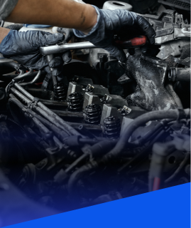 A close-up of a mechanic’s hands in black gloves using a wrench to perform maintenance on an open car engine. | Heaven Sent Automotive
