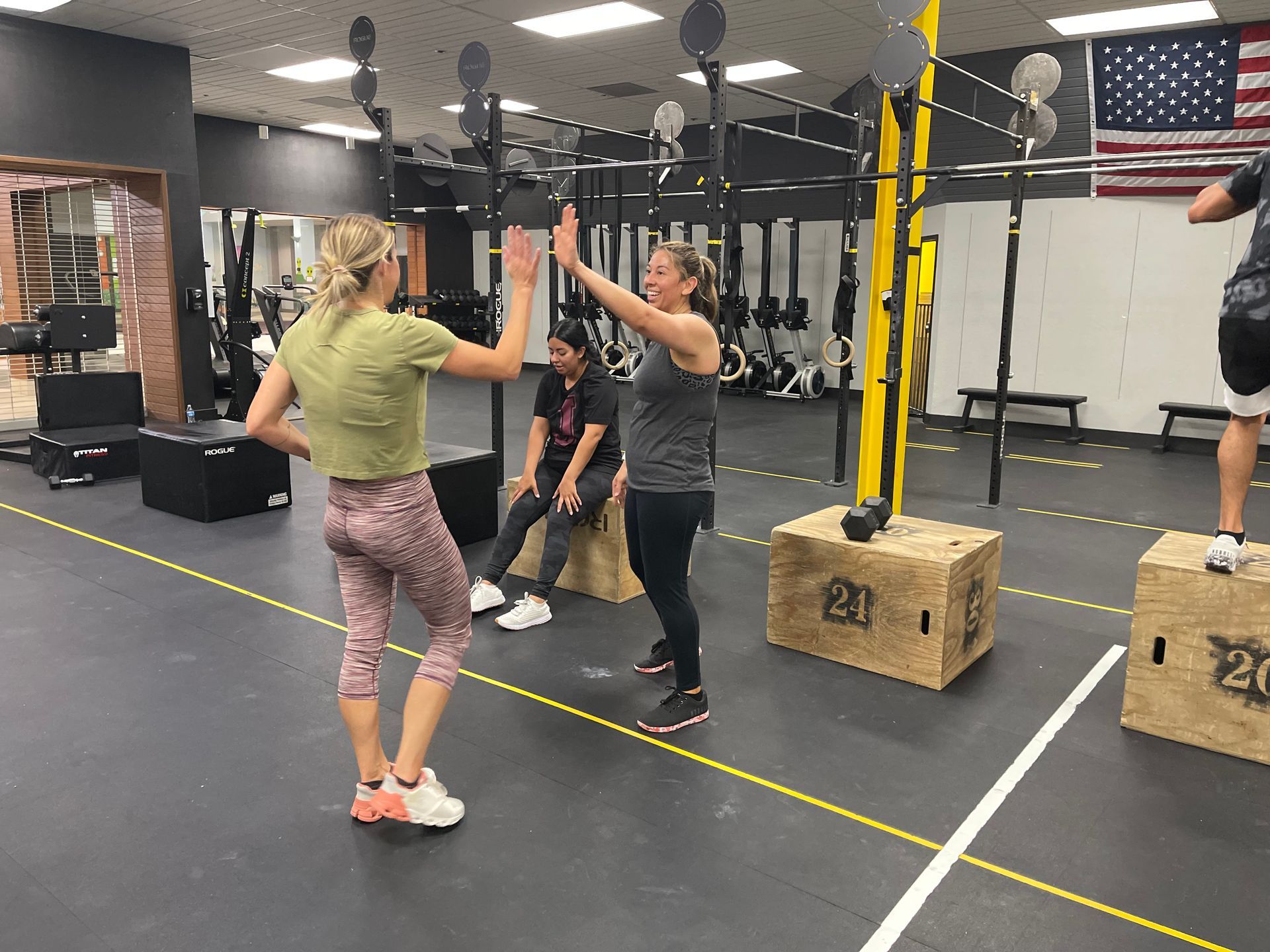 A man is helping a woman lift dumbbells on a bench.