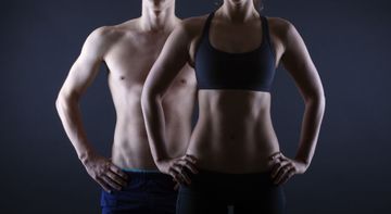 A man and a woman are standing next to each other with their hands on their hips.