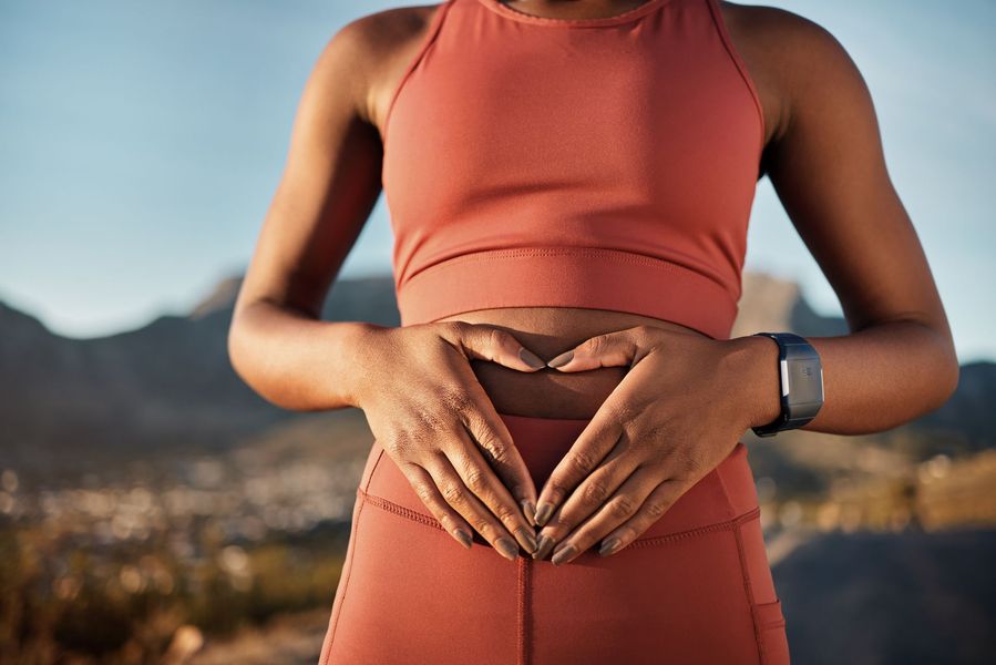 A woman is making a heart shape with her hands on her stomach.
