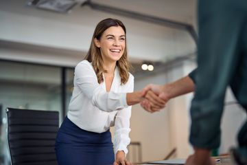 A woman is shaking hands with a man in an office.