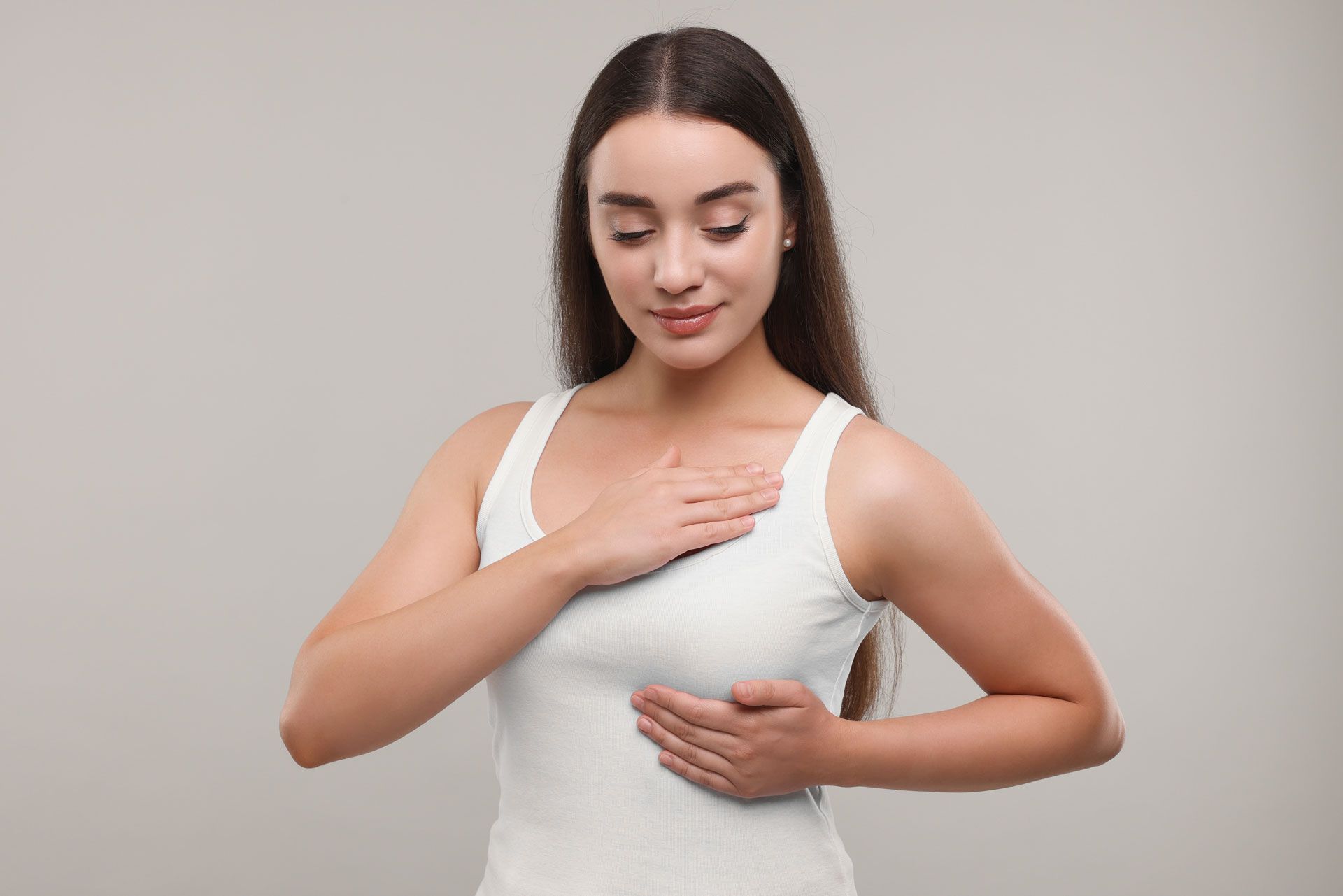 Woman wearing black bra, hand on shoulder, black background.