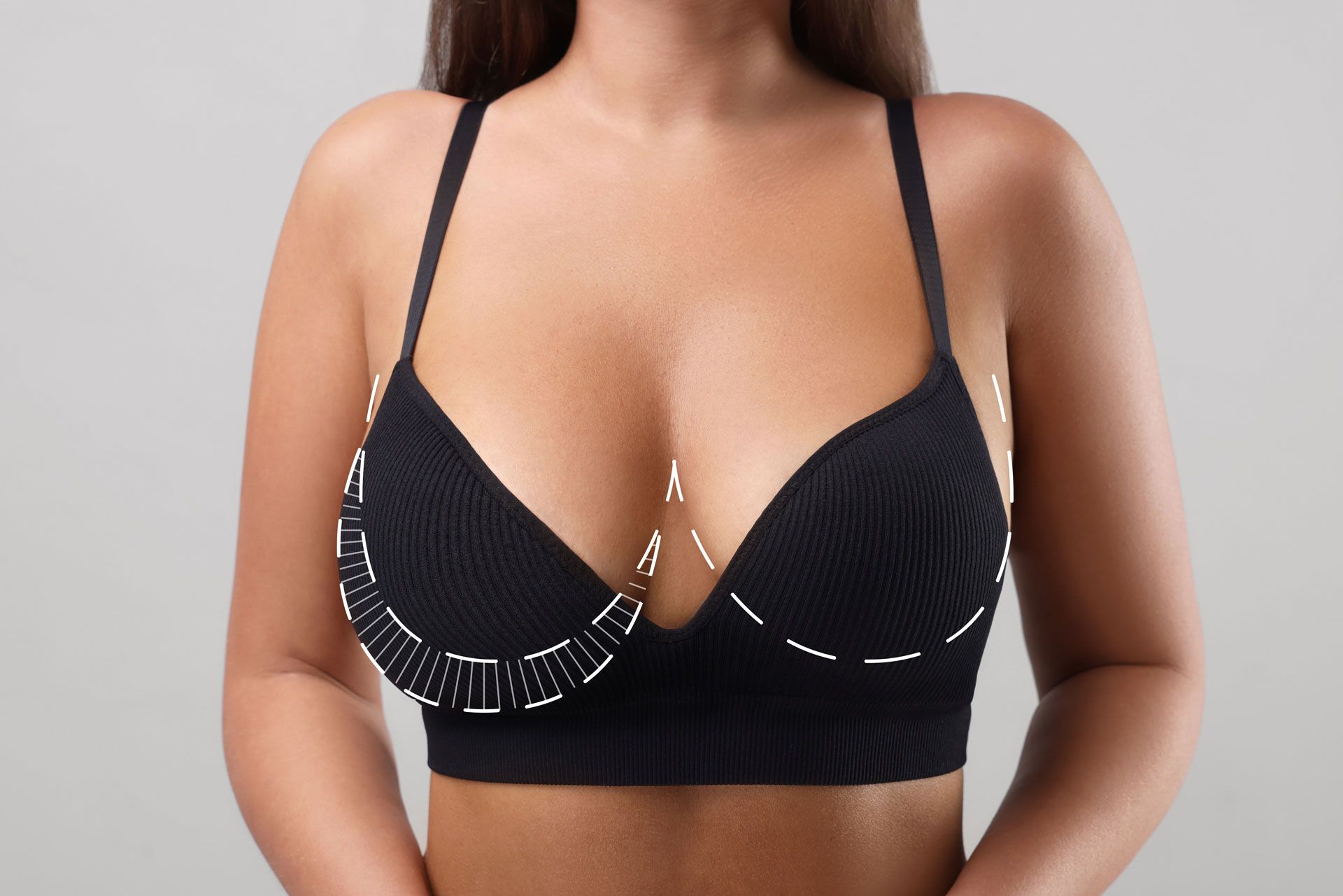 A black sports bra worn by a person, with dashed lines illustrating the bra's fit and support structure.