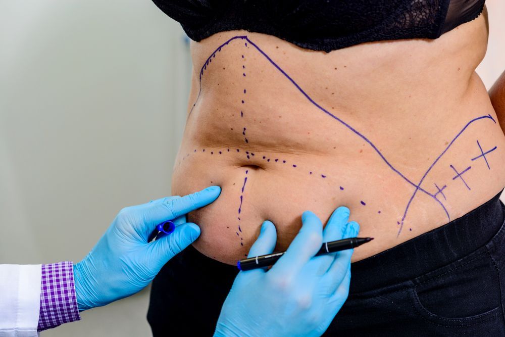 Gloved hands using a glowing handheld device on a person’s bare abdomen during a skin treatment