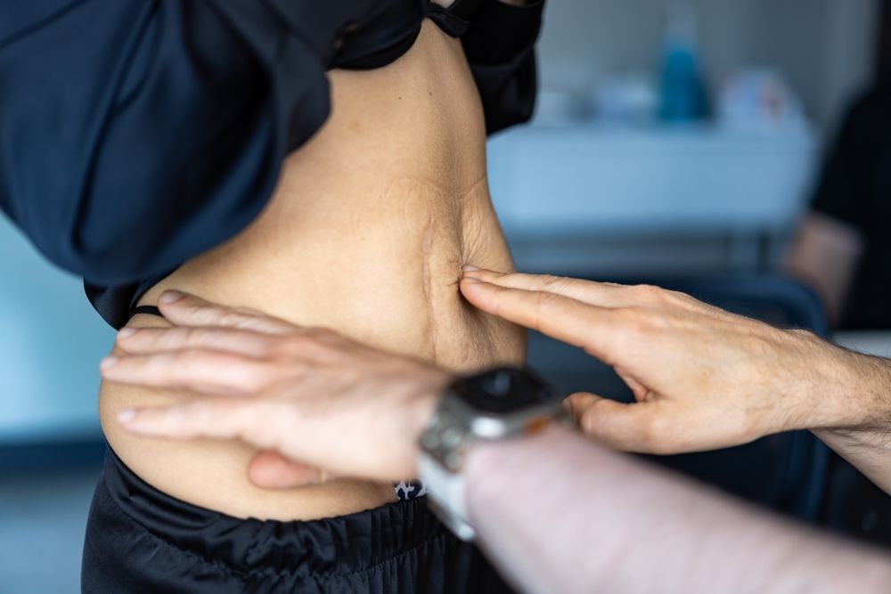 Hands assessing a person’s lower back during a physical therapy or massage session