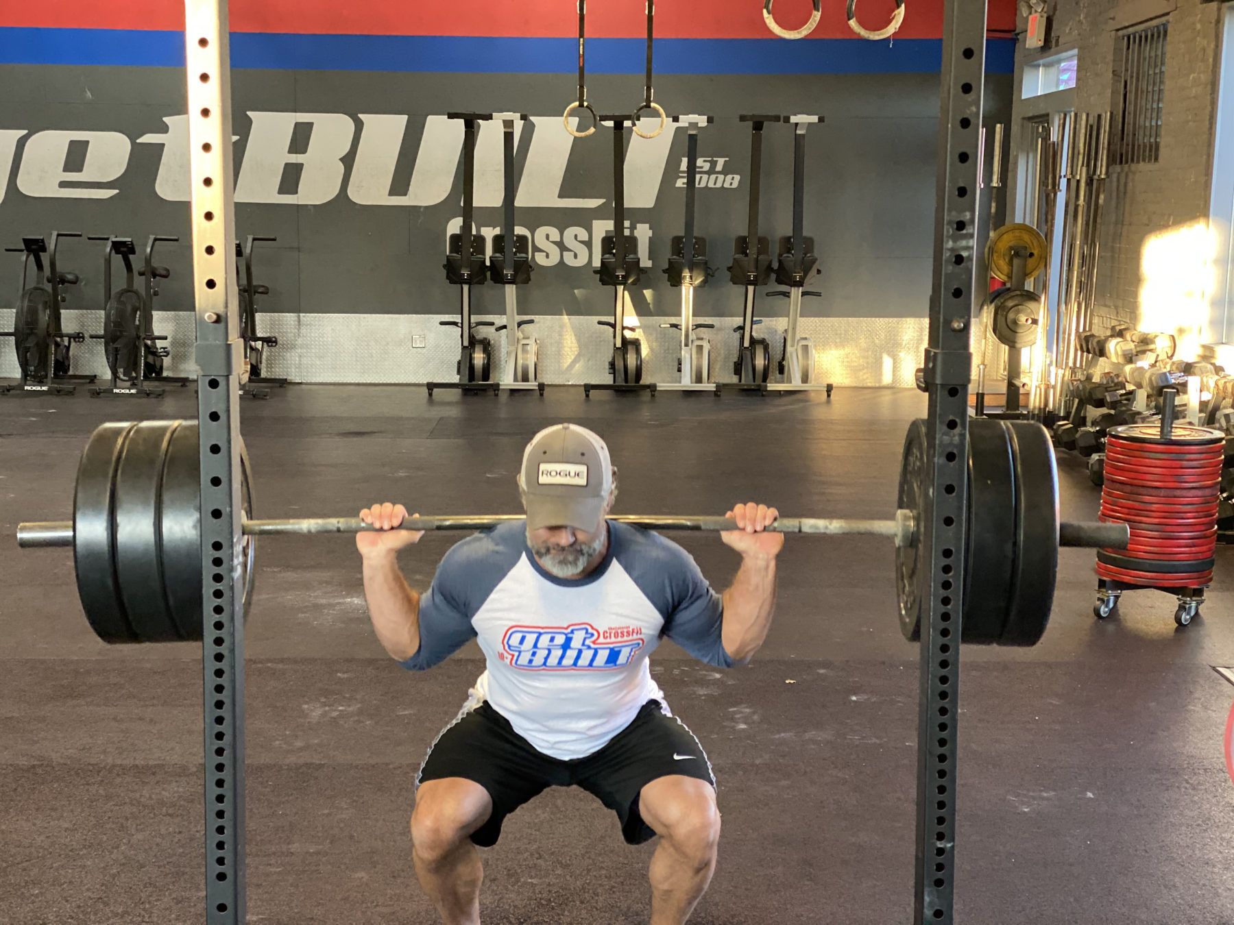 A man squatting with a barbell in a gym