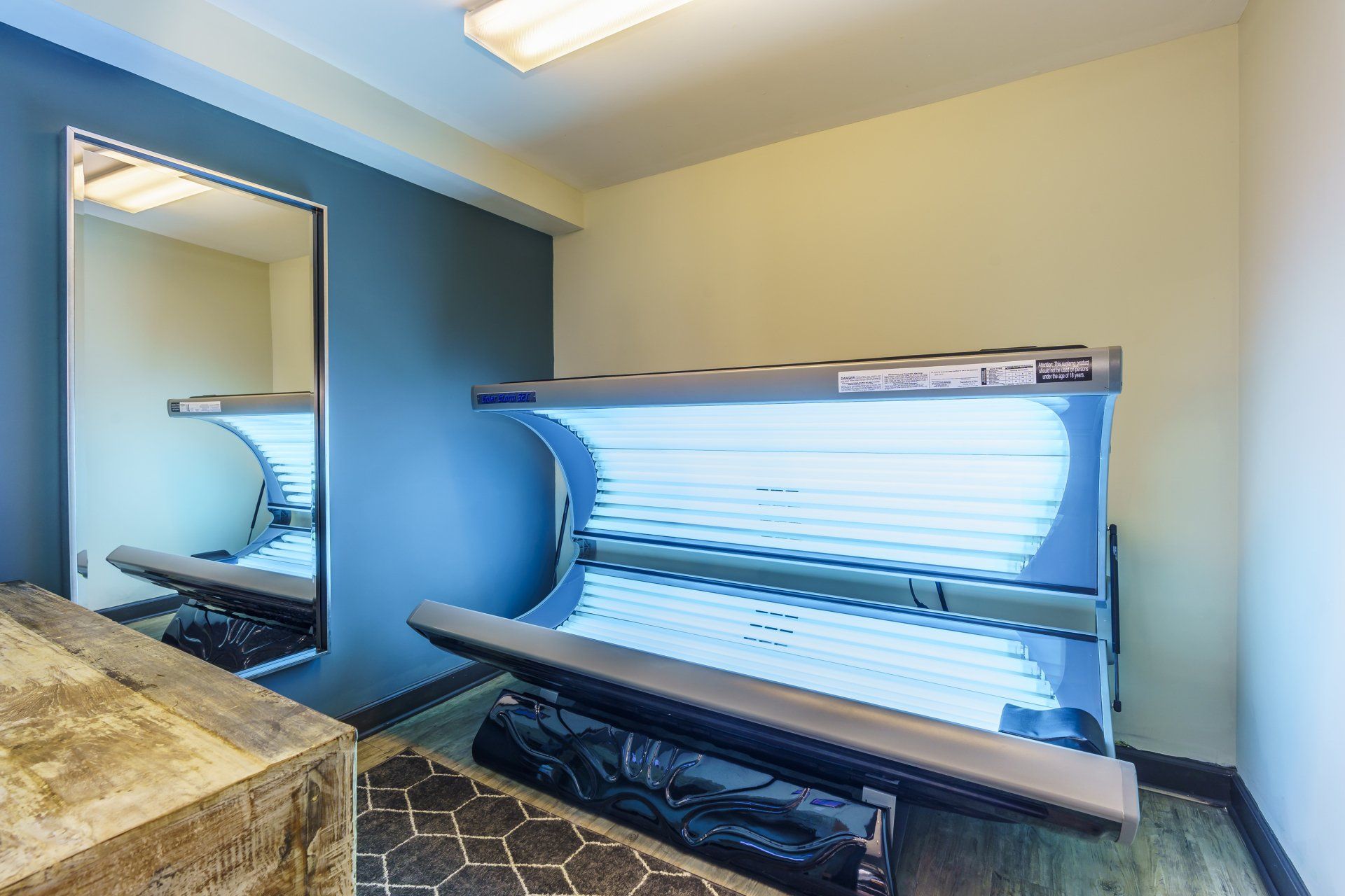 A room with two tanning beds and a mirror.