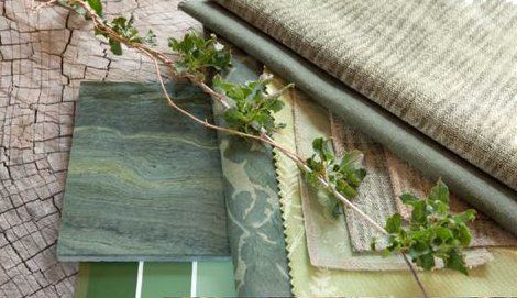 Green and tan fabric swatches with a sprig of greenery on a textured wooden surface.