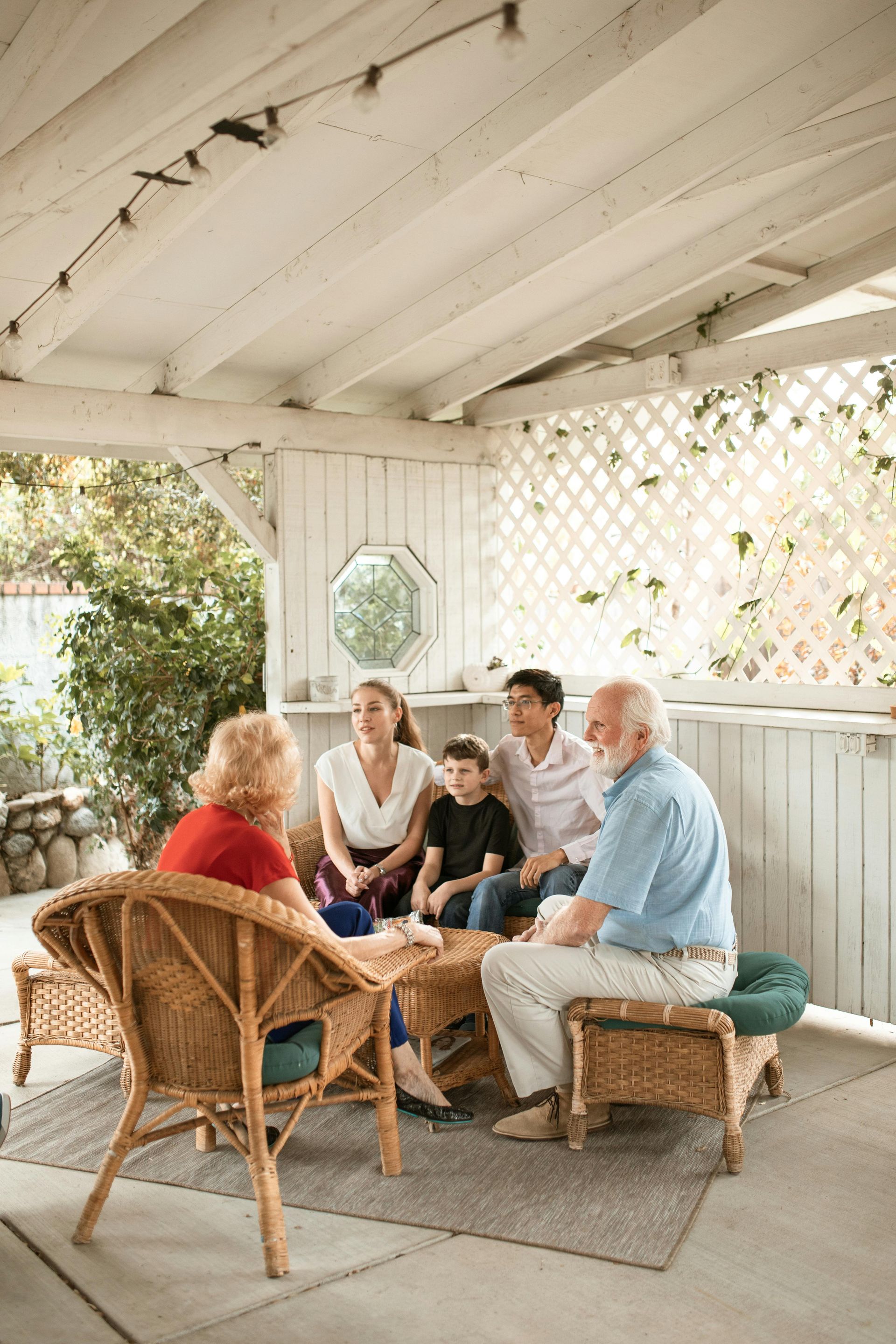 A family is sitting on a porch talking to each other.