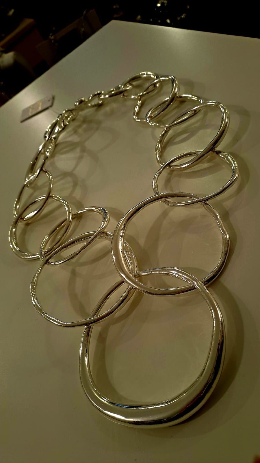 Una collana d'argento è appoggiata su un tavolo bianco.