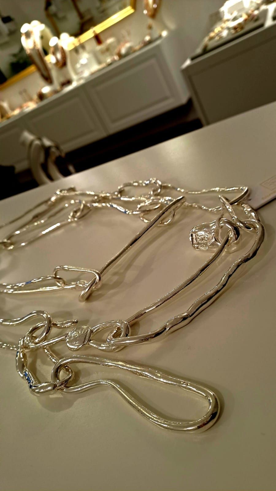 Una collana d'argento è appoggiata su un tavolo bianco.