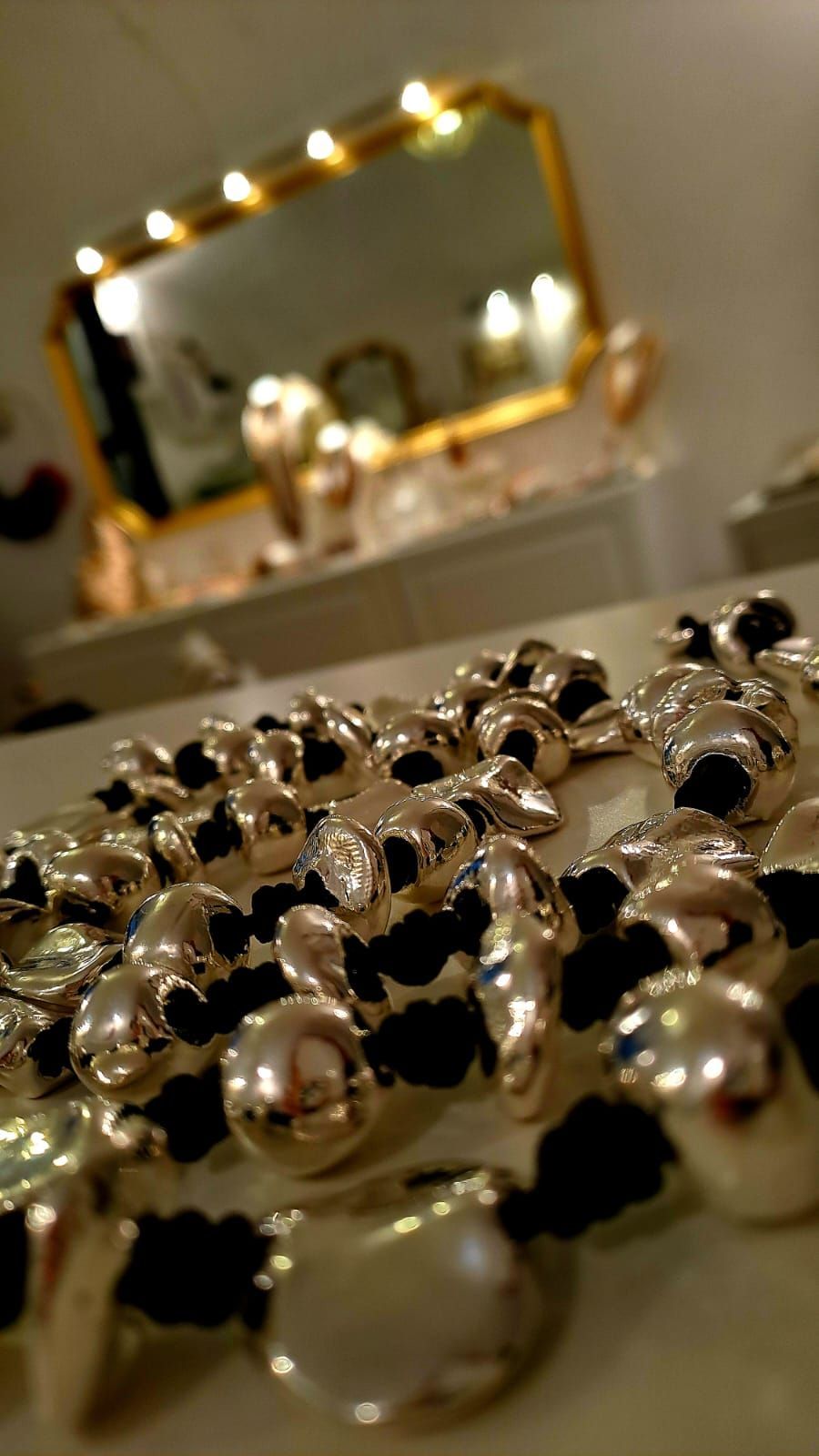 Un mazzo di anelli d'argento è appoggiato su un tavolo davanti a uno specchio.