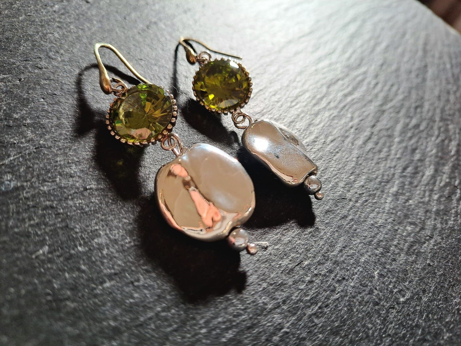 Un paio di orecchini sono appoggiati su una superficie nera