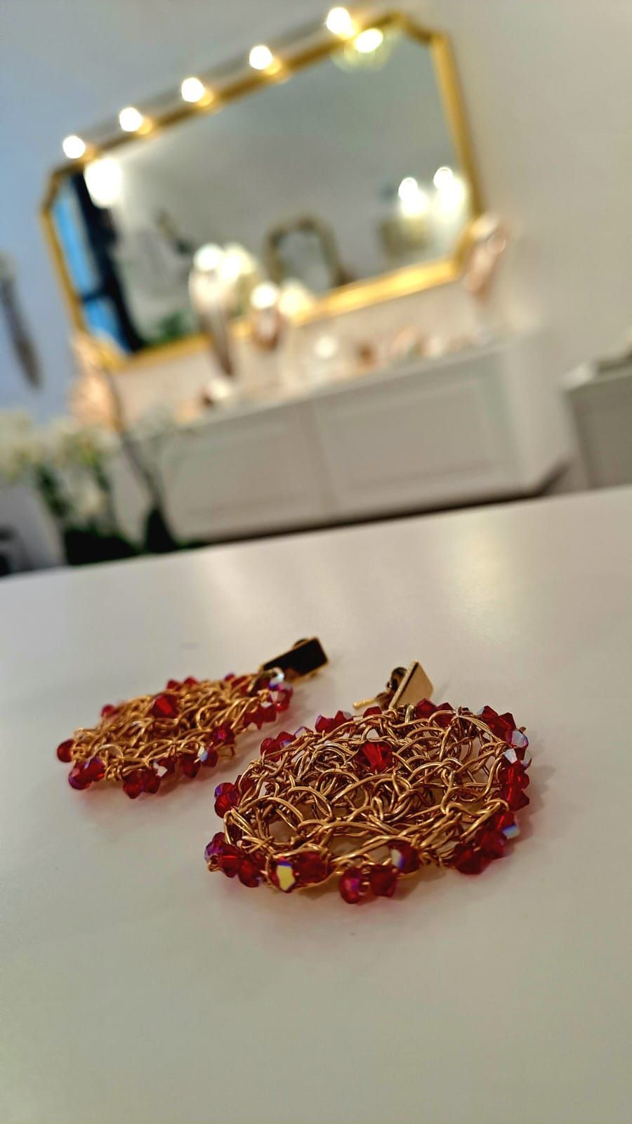 Un paio di orecchini sono appoggiati su un tavolo davanti a uno specchio.