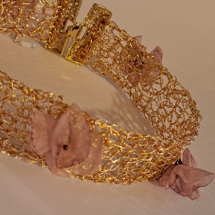 Un braccialetto d'oro con fiori rosa