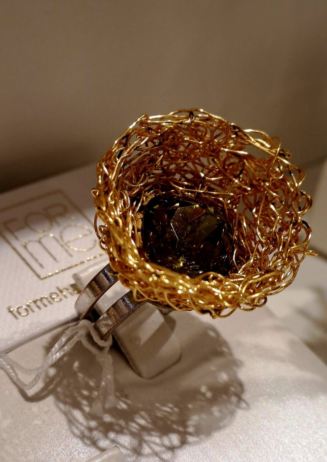 Un anello d'oro è appoggiato su un tavolo bianco