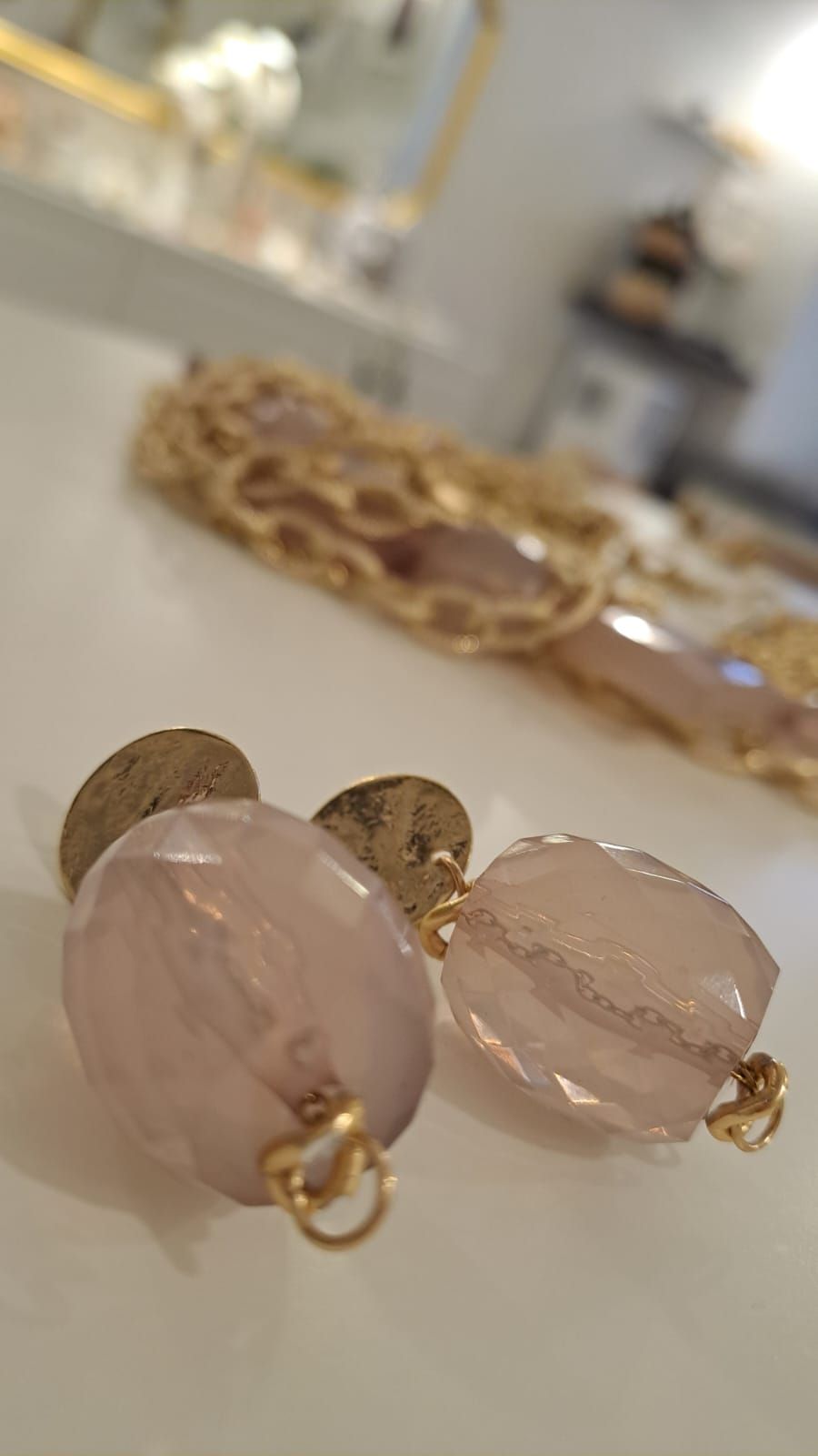 Un paio di orecchini sono appoggiati su un tavolo accanto a una collana.