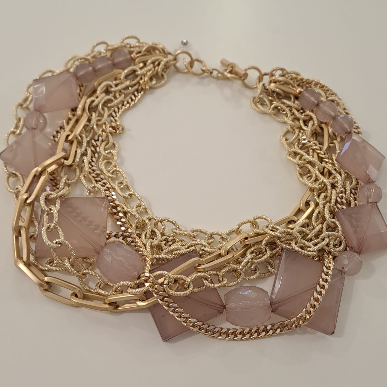 Una collana fatta di catene d'oro e perline rosa