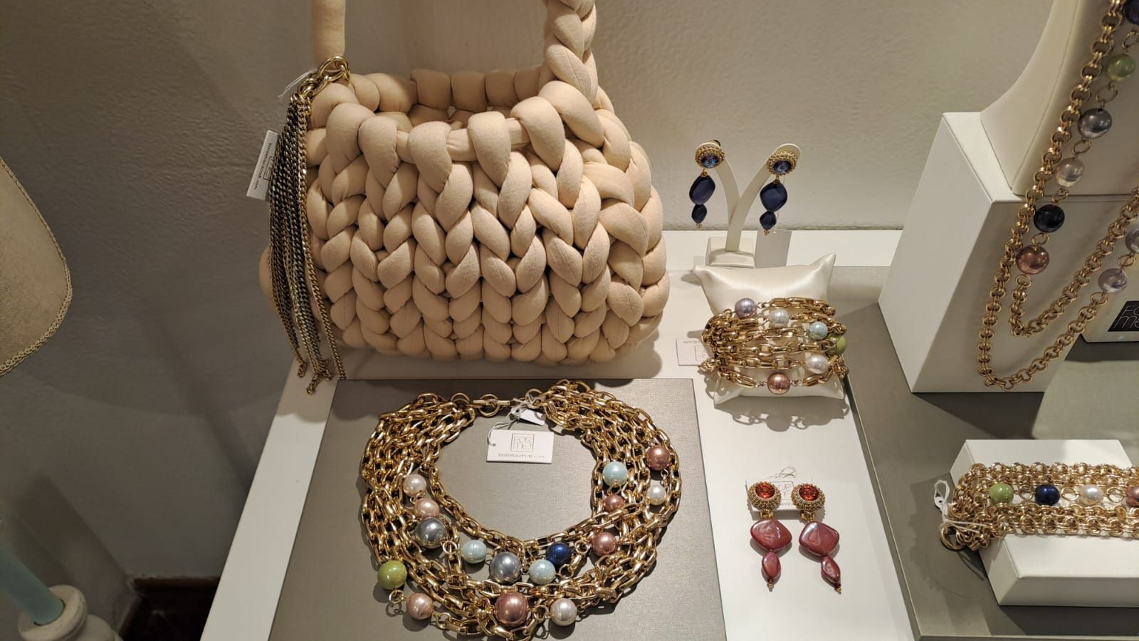 Un tavolo con una borsa, una collana, degli orecchini e dei braccialetti sopra