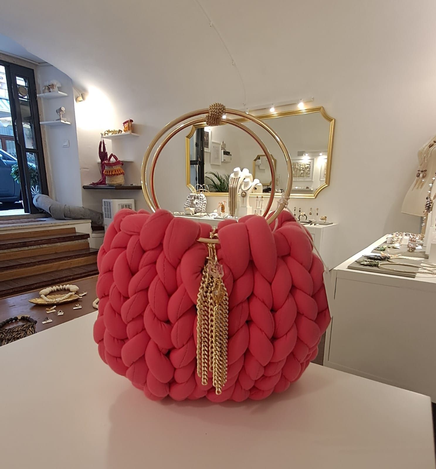 Una borsa rosa con un manico dorato è appoggiata su un tavolo