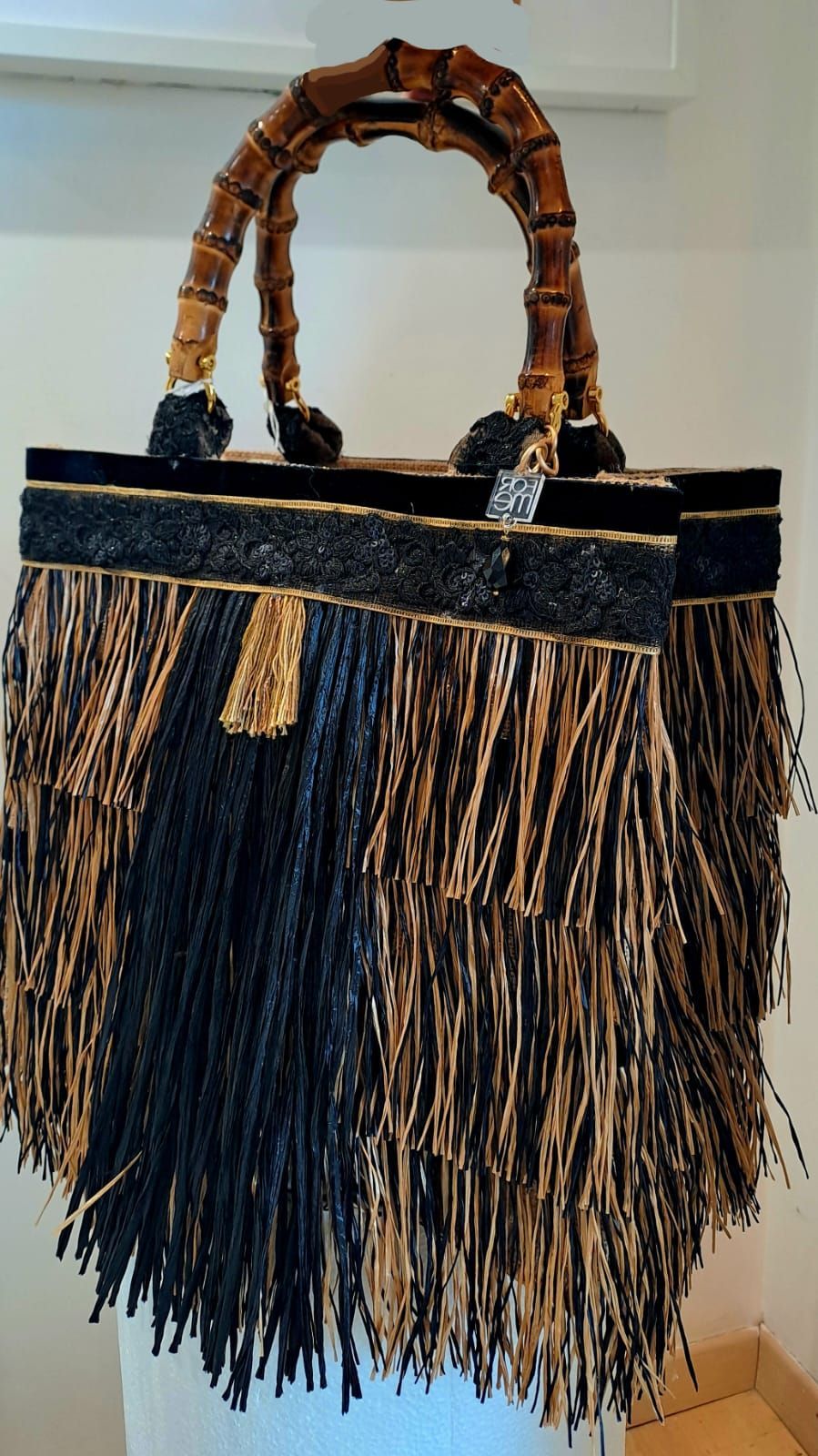 Una borsa nera e marrone con frange e manici di bambù