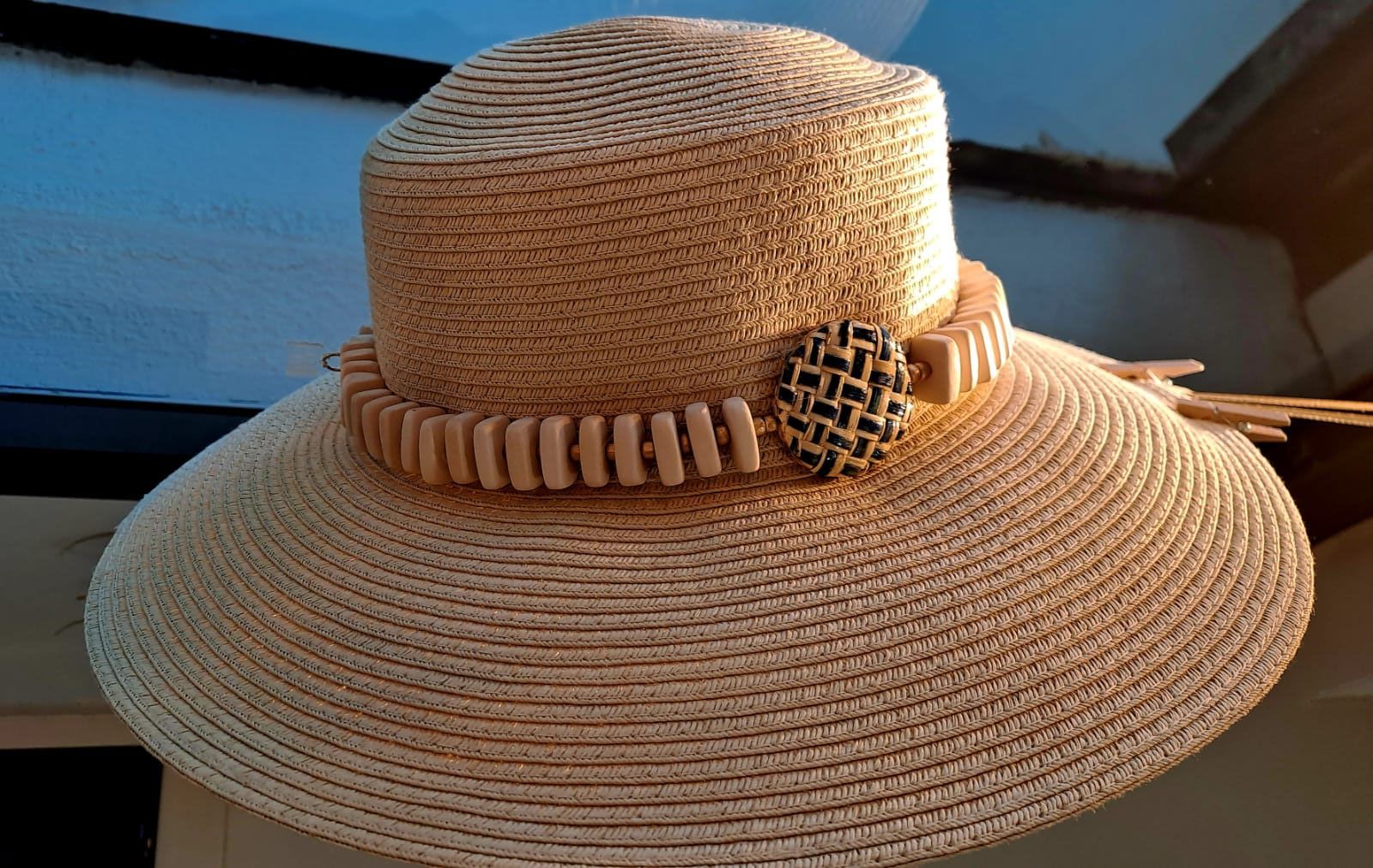 Un cappello di paglia con un fiore è appoggiato su un tavolo.