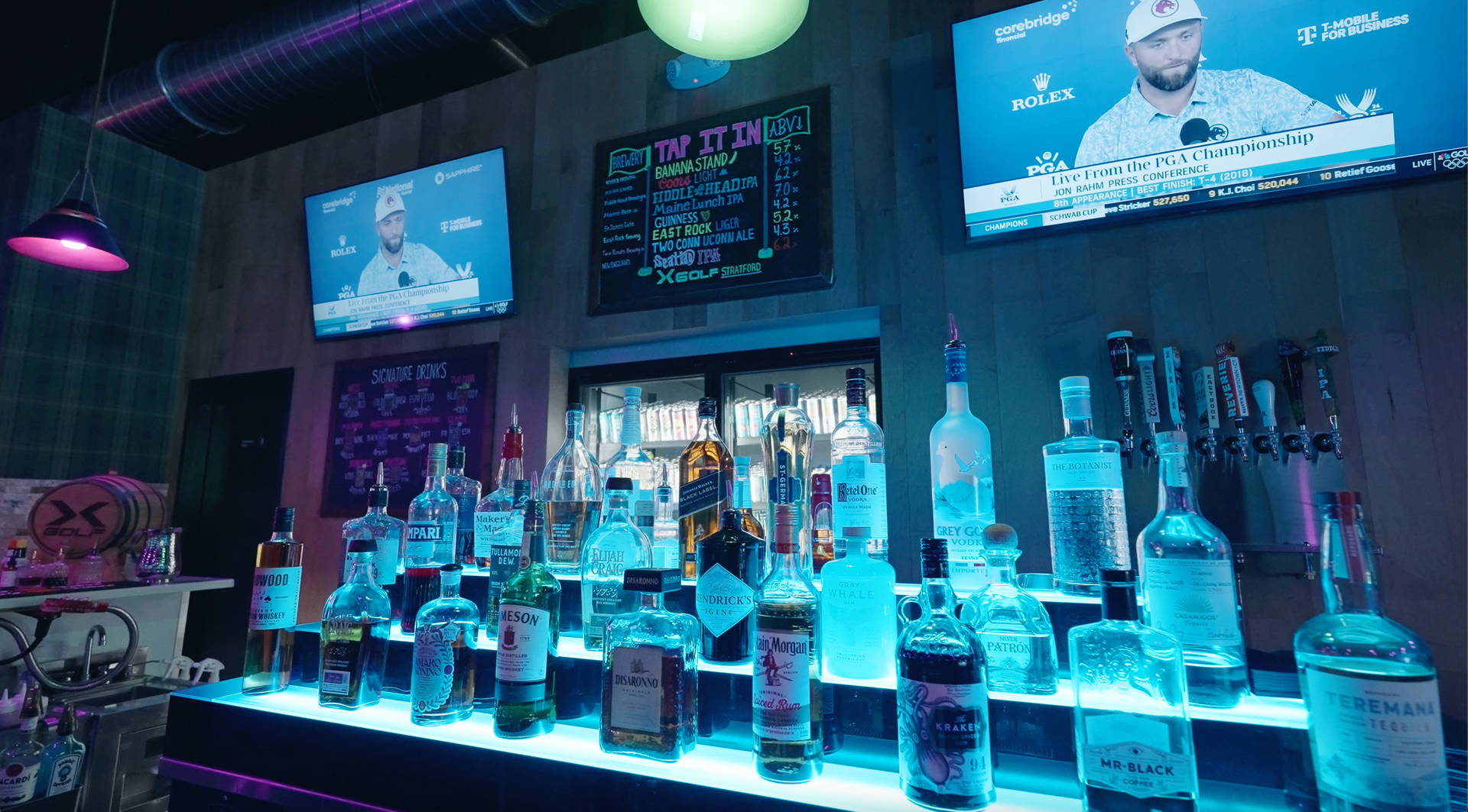 A bar filled with lots of bottles of alcohol and two televisions.