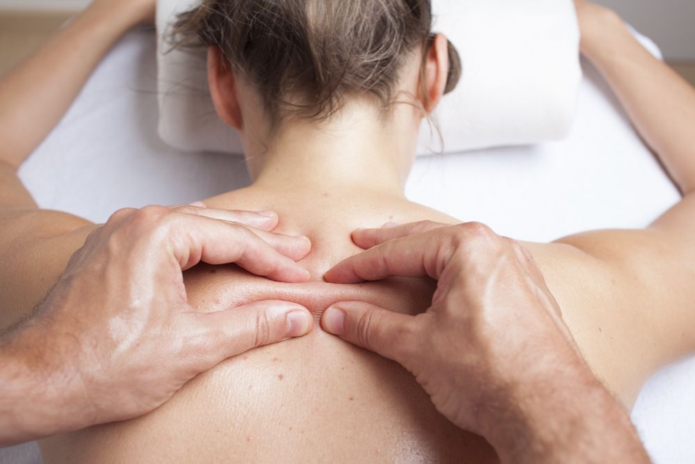 A woman is getting a massage on her back by a man.
