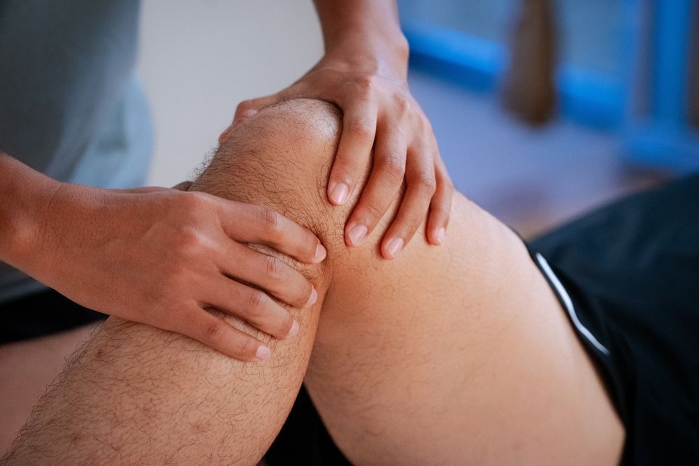 A person is giving a man a massage on his knee.