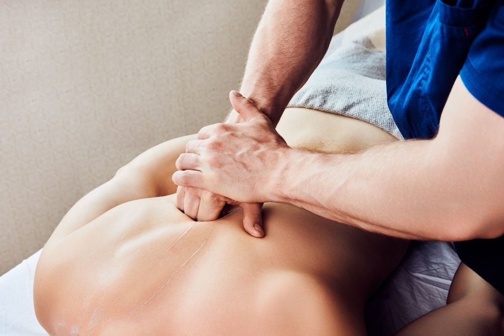 A man is giving a woman a massage on her back.