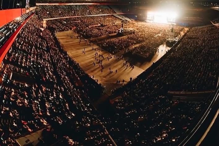 A large crowd of people are gathered in a stadium at night at iTickets show. 