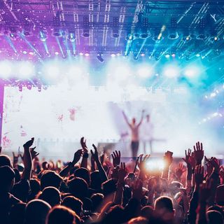 A crowd of people are raising their hands in the air at a concert.