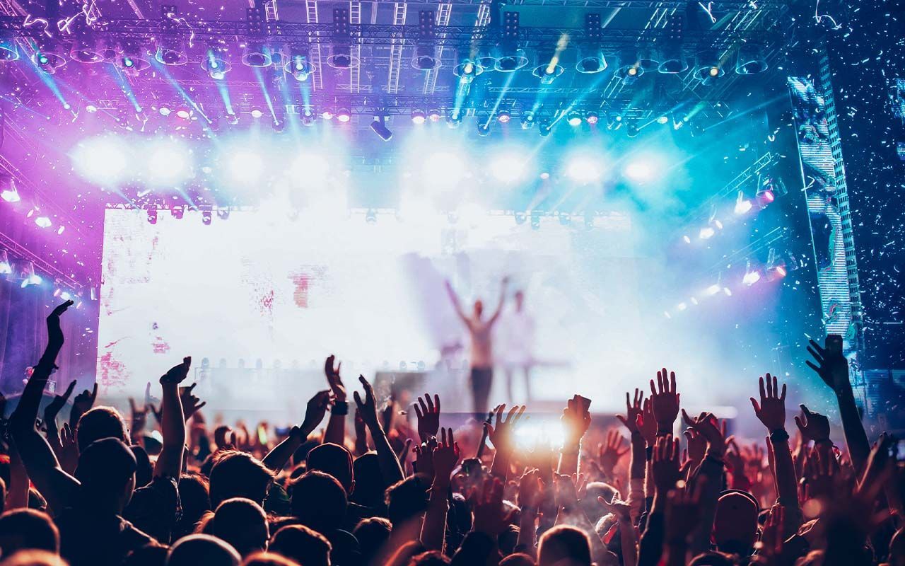 A crowd of people are raising their hands in the air at a concert.