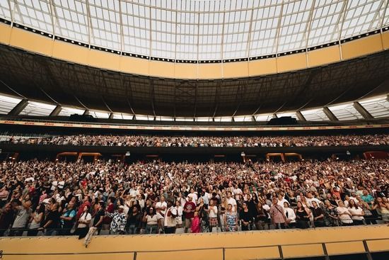 A crowd of people are raising their hands in the air at a concert.