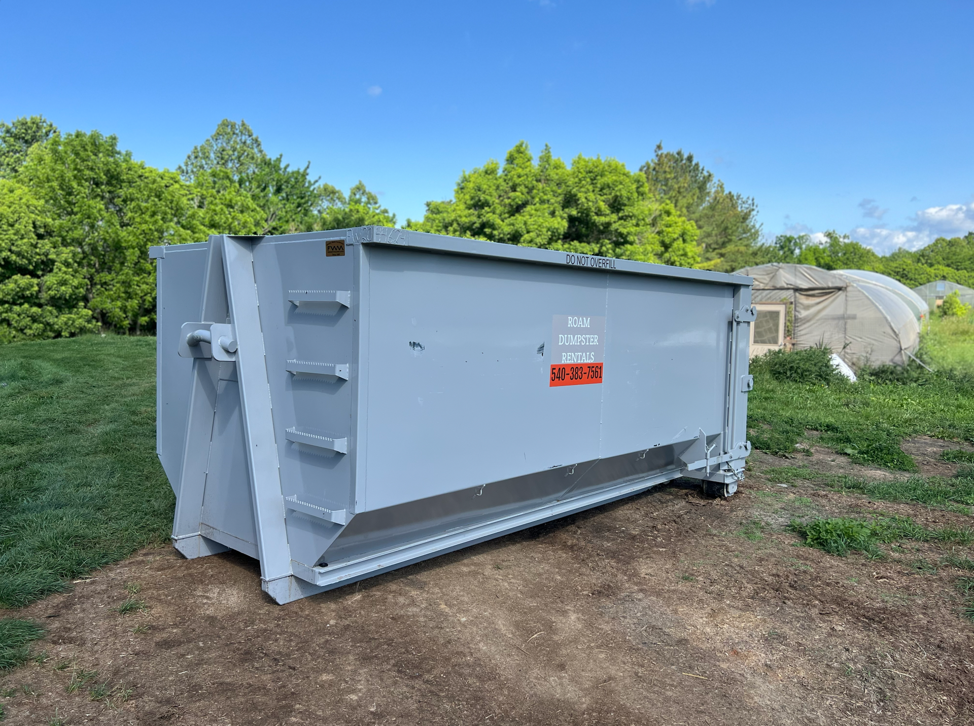 Large 15 yard black dumpster with 'ROAM' company logo on it.