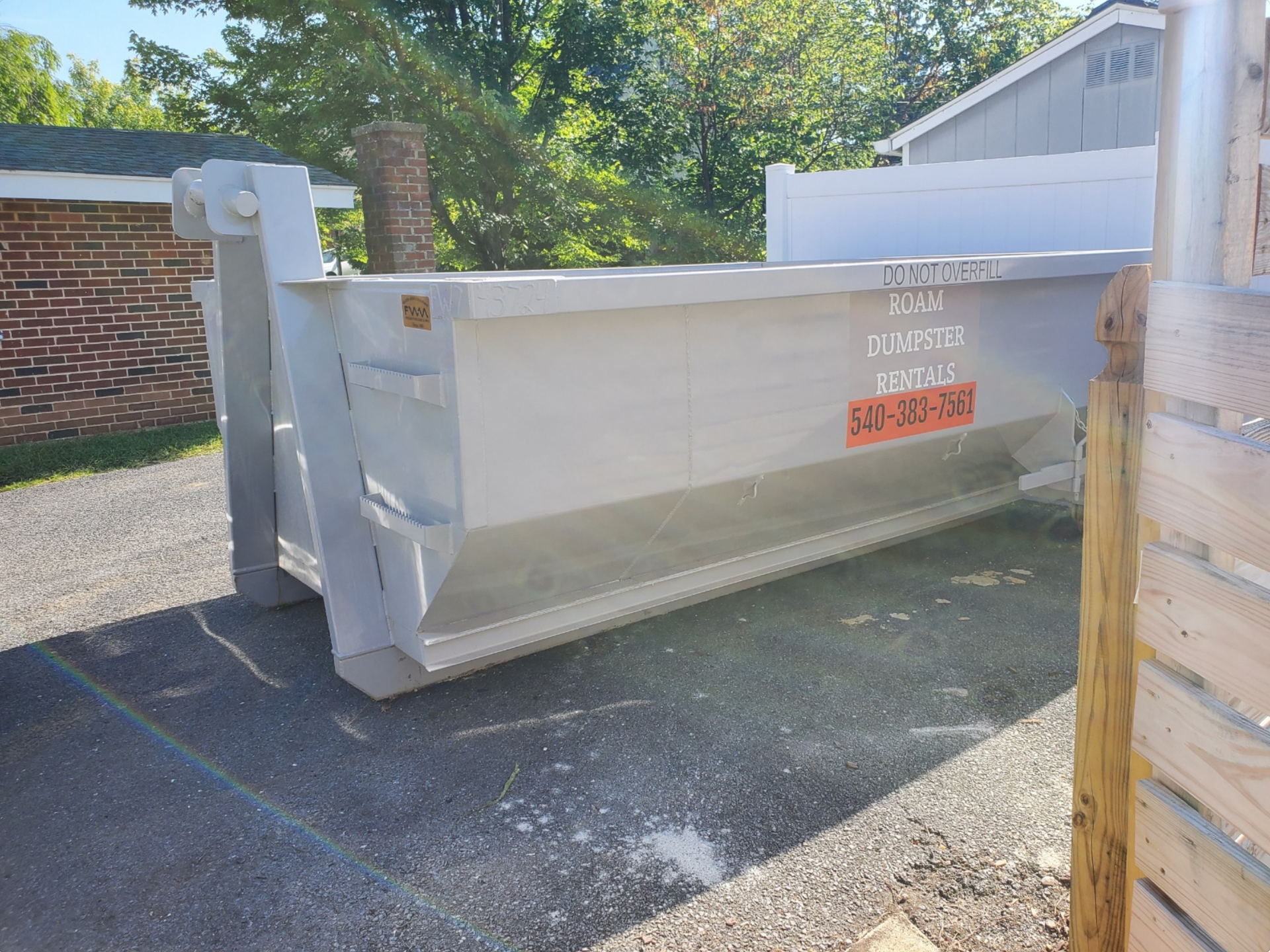 A dumpster is being towed by a truck in a parking lot.