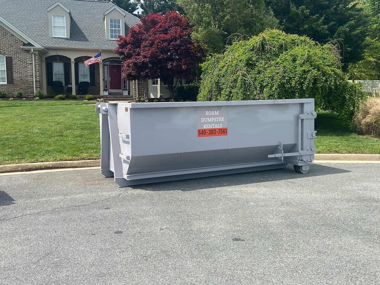 A large 20 yard dumpster is parked in front of a house.