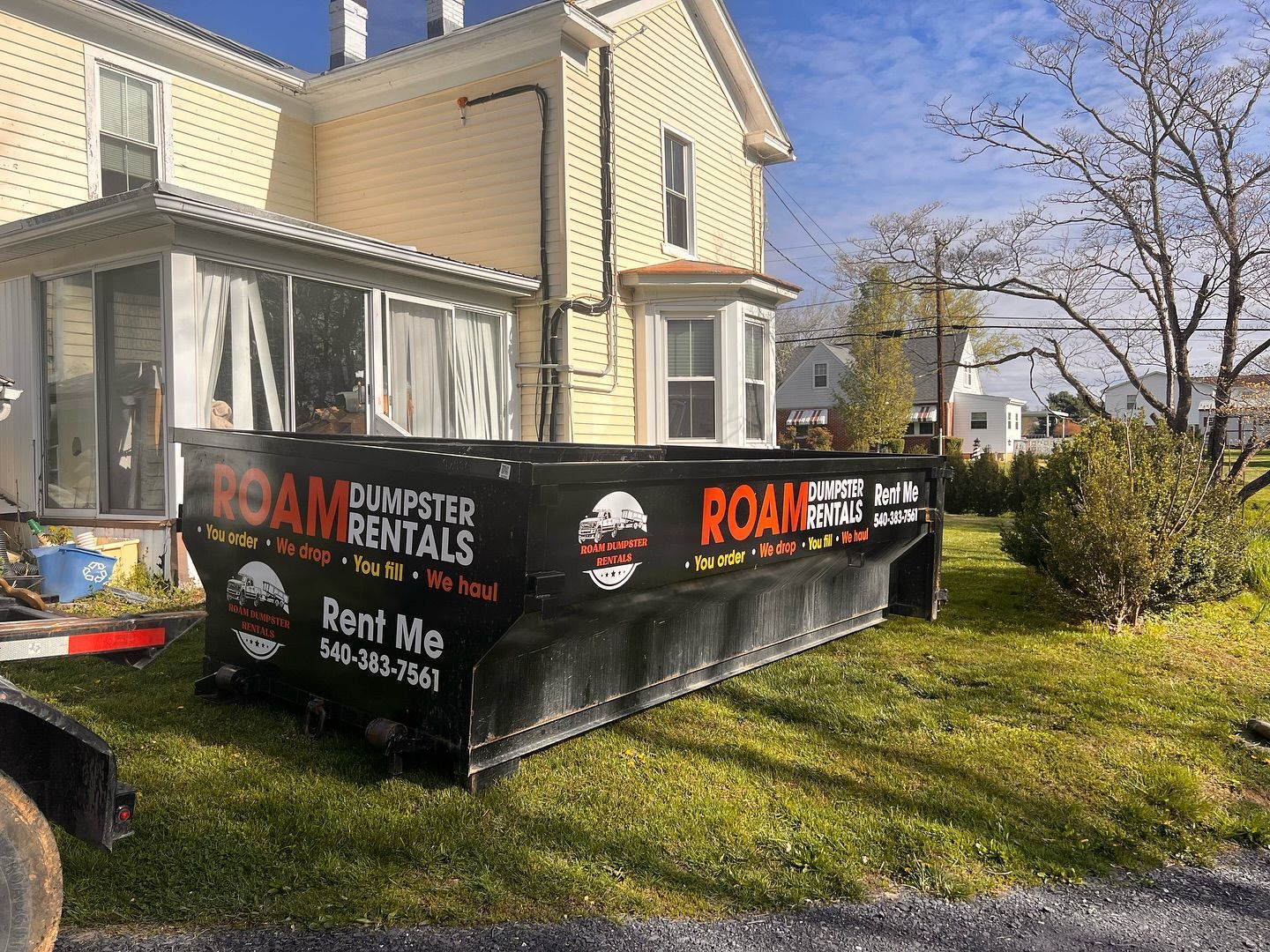 A dumpster is parked in front of a house.