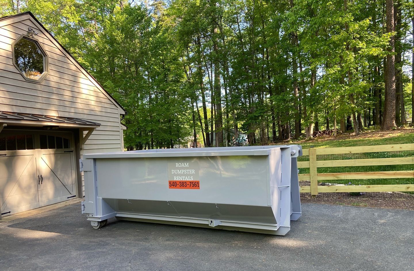 A large dumpster is parked in front of a house.