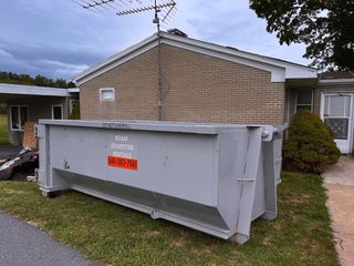 A large dumpster is sitting in front of a house.