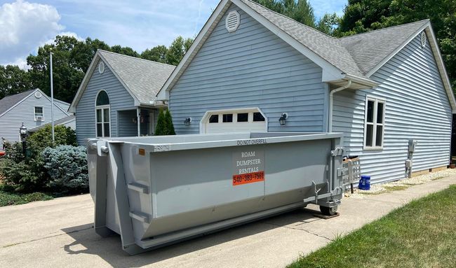 A large dumpster is parked in front of a house.