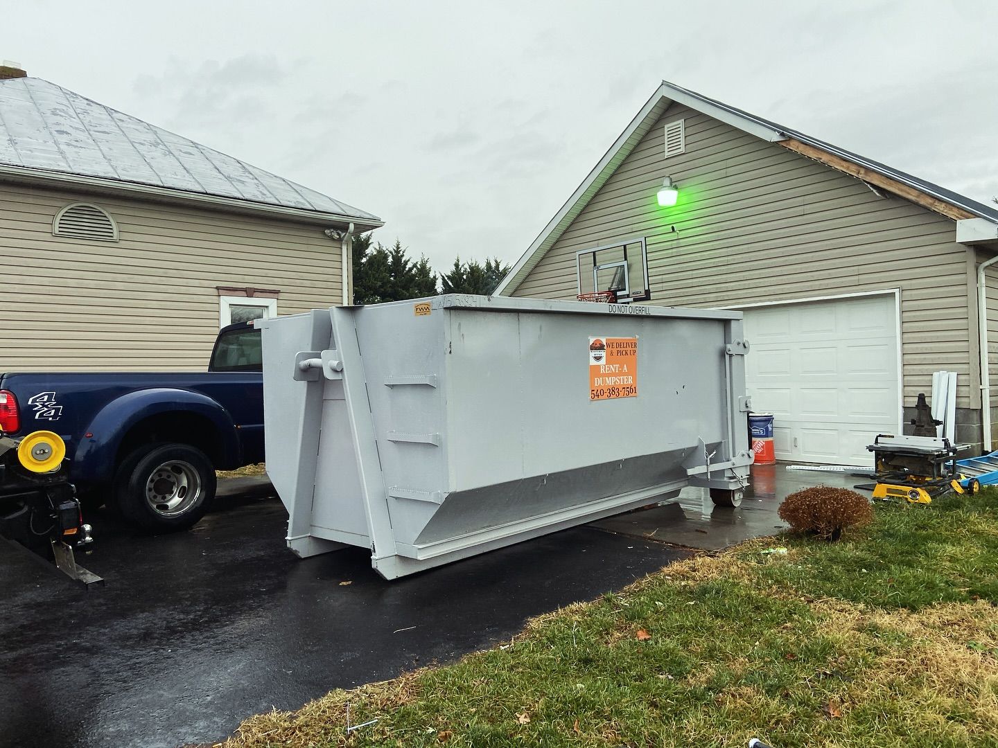 A large dumpster is parked in front of a house.