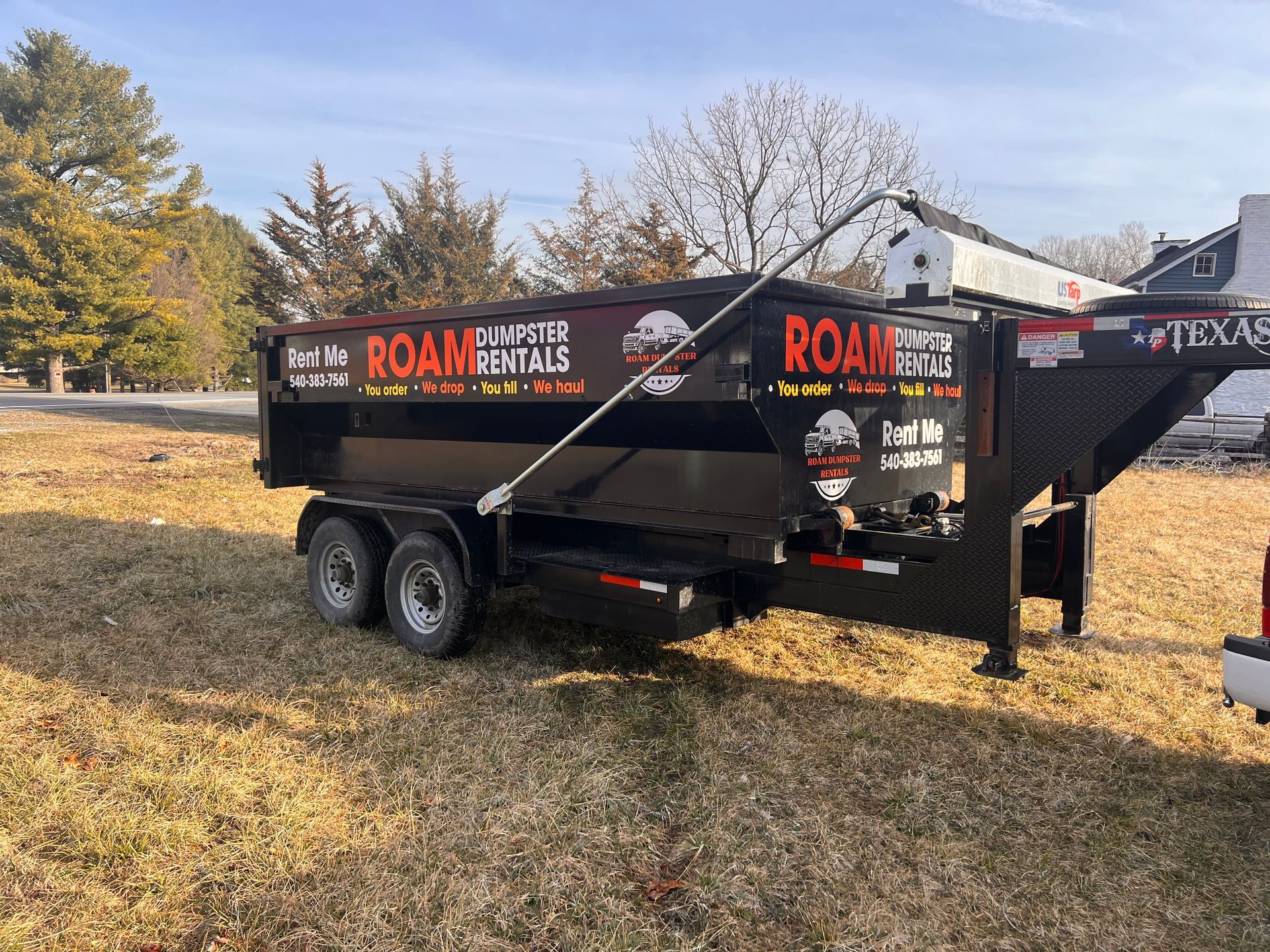 A dumpster trailer is parked in a grassy field.