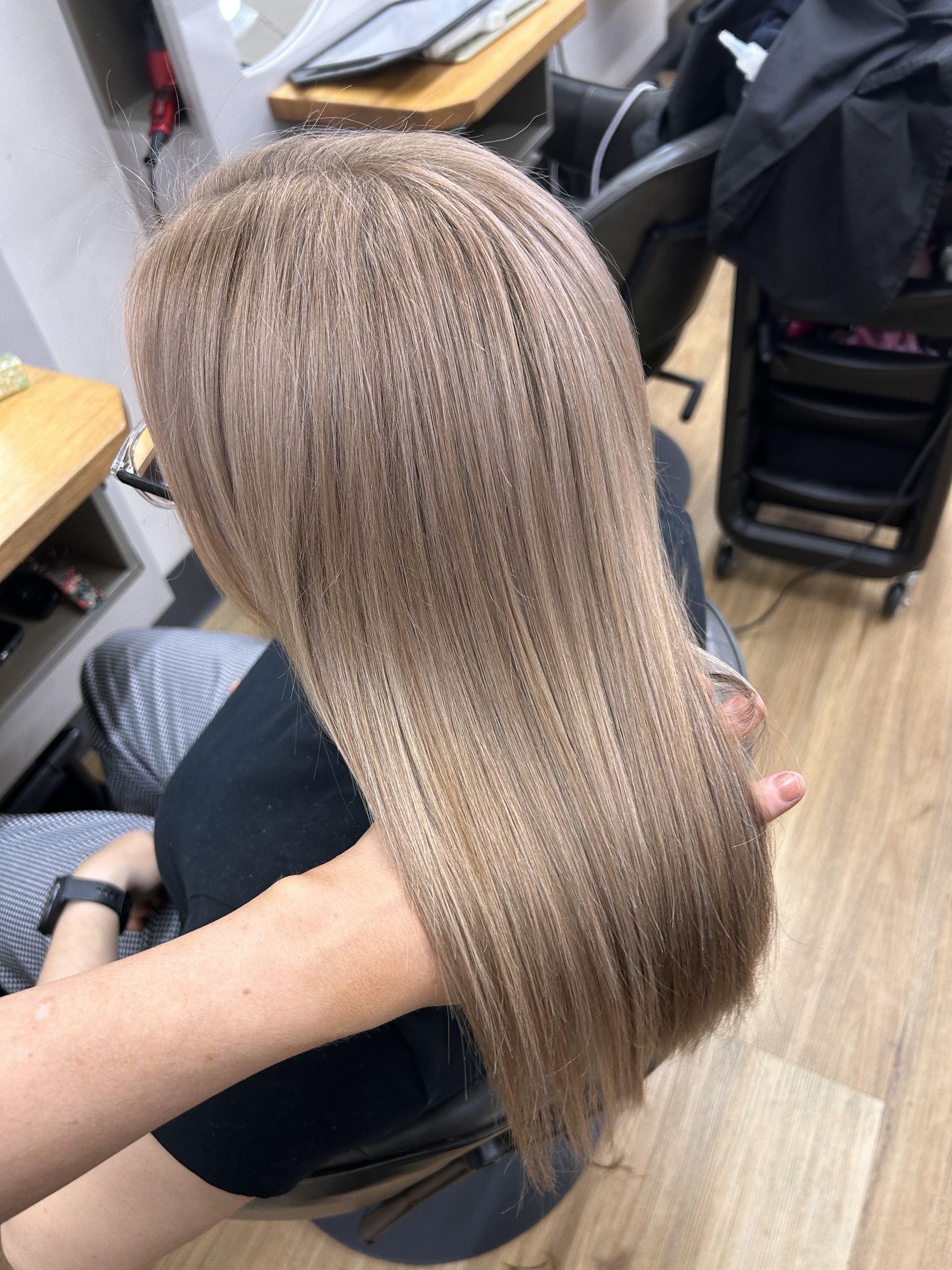 Long straight light brown hair with subtle highlights, viewed from above in a salon chair.