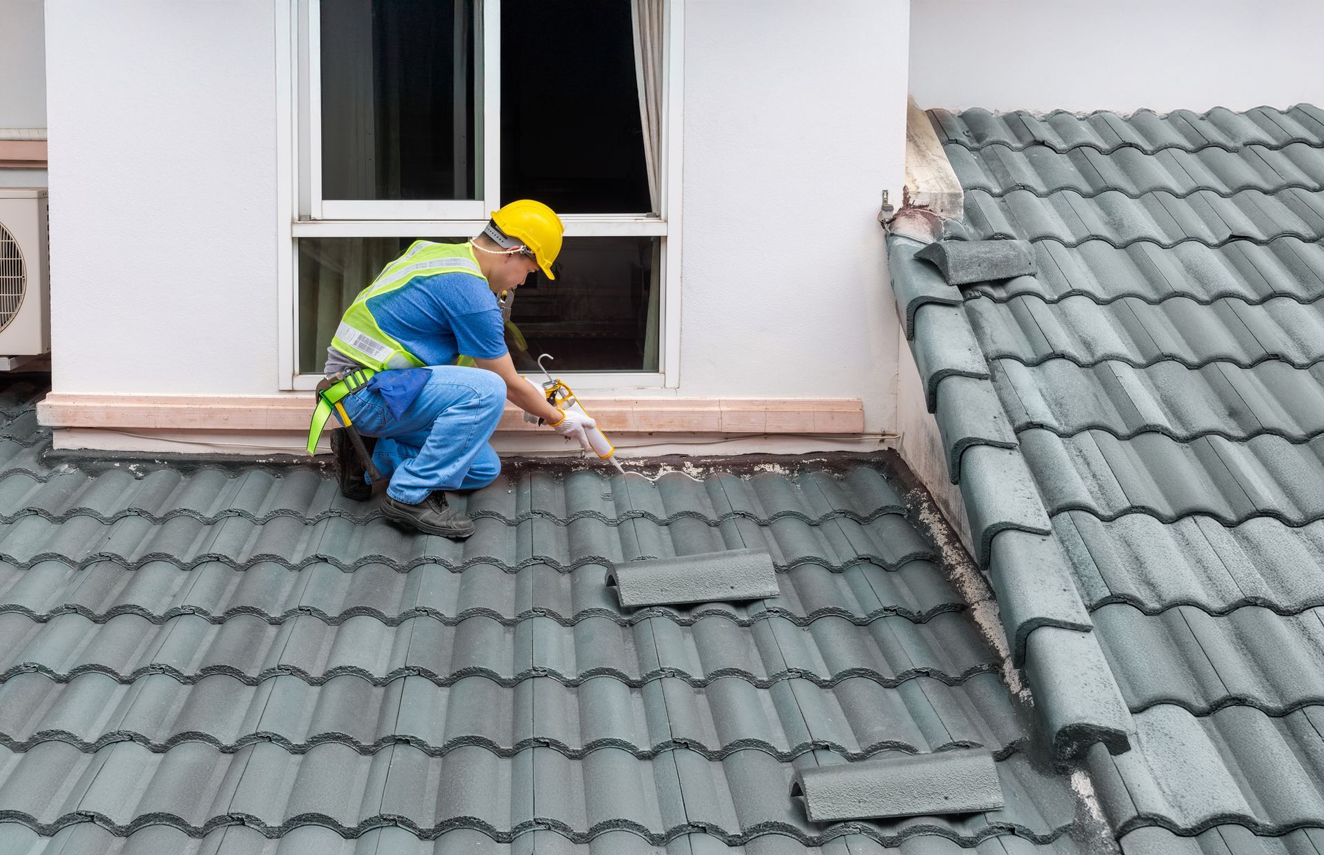 A roofer is performing roofing repair services, using silicone sealant to fix a crack on a roof. A roofer is performing roofing repair services, using silicone sealant to fix a crack on a roof.
