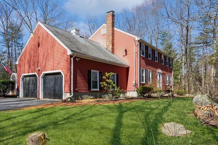 A large red house with two garages and a large lawn in front of it.