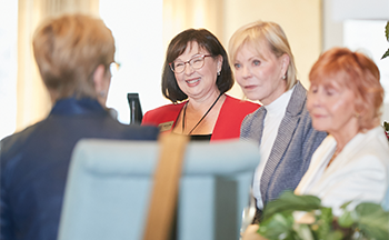 A group of women are sitting in a room talking to each other.