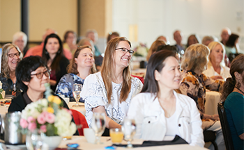 A group of people are sitting at tables at a conference.