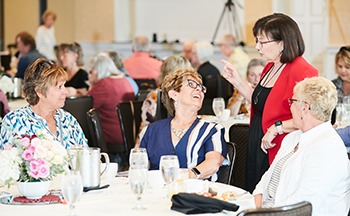 A group of women are sitting at a table talking to each other.